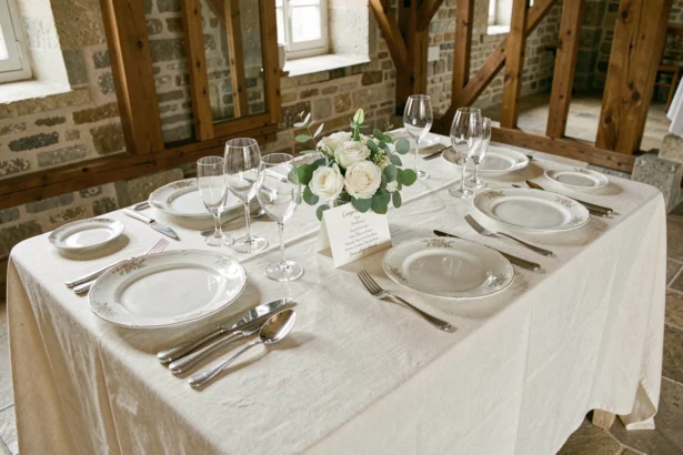 Table de mariage élégamment dressée avec vaisselle fine, verres en cristal et menu calligraphié dans un château rustique